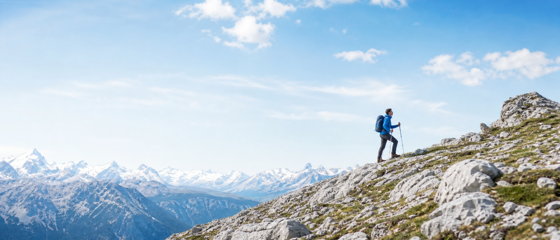 Hiker ascending a bright alpine mountain ridge in blue outdoor apparel