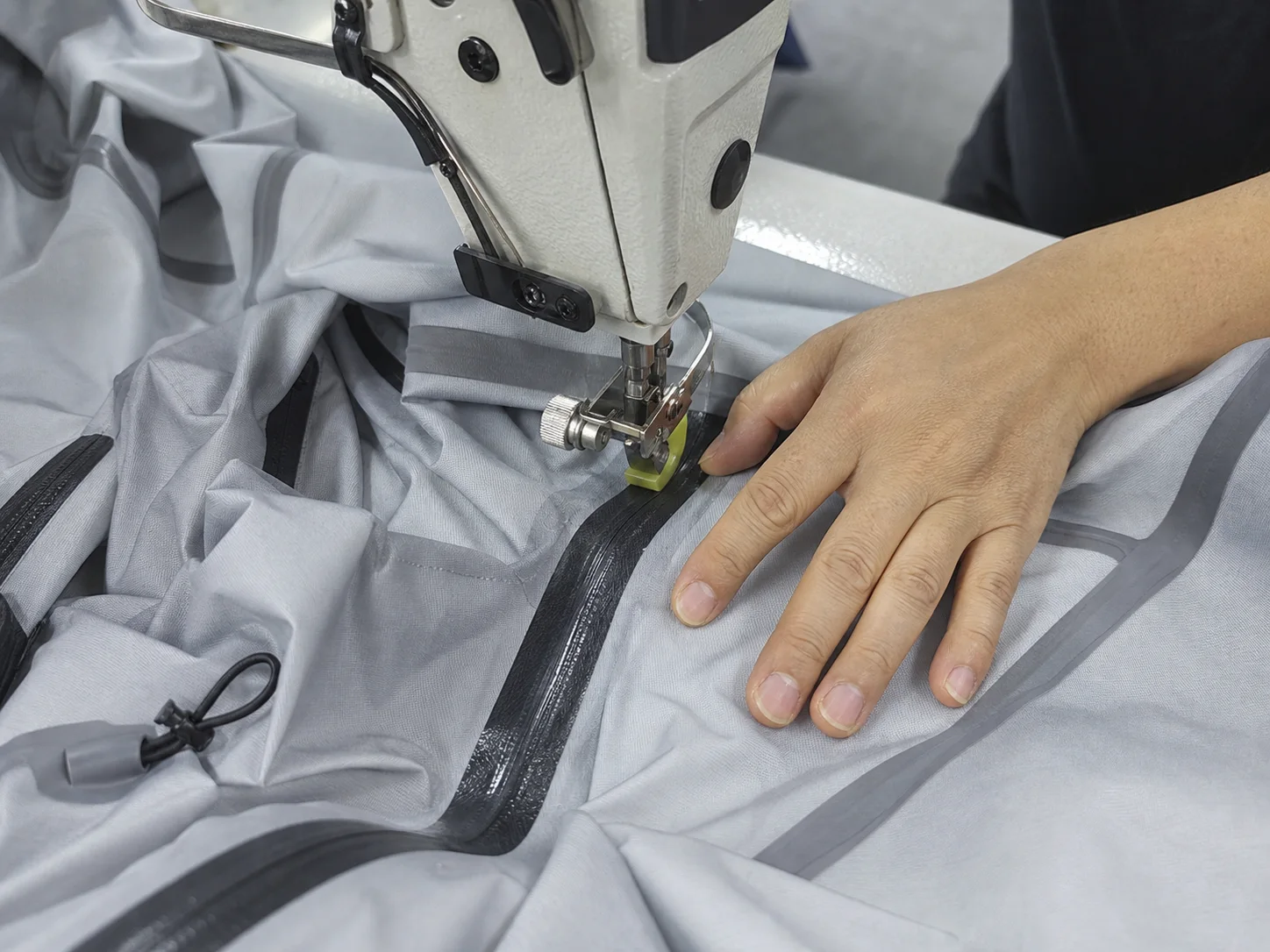 Technician heat sealing a waterproof jacket seam