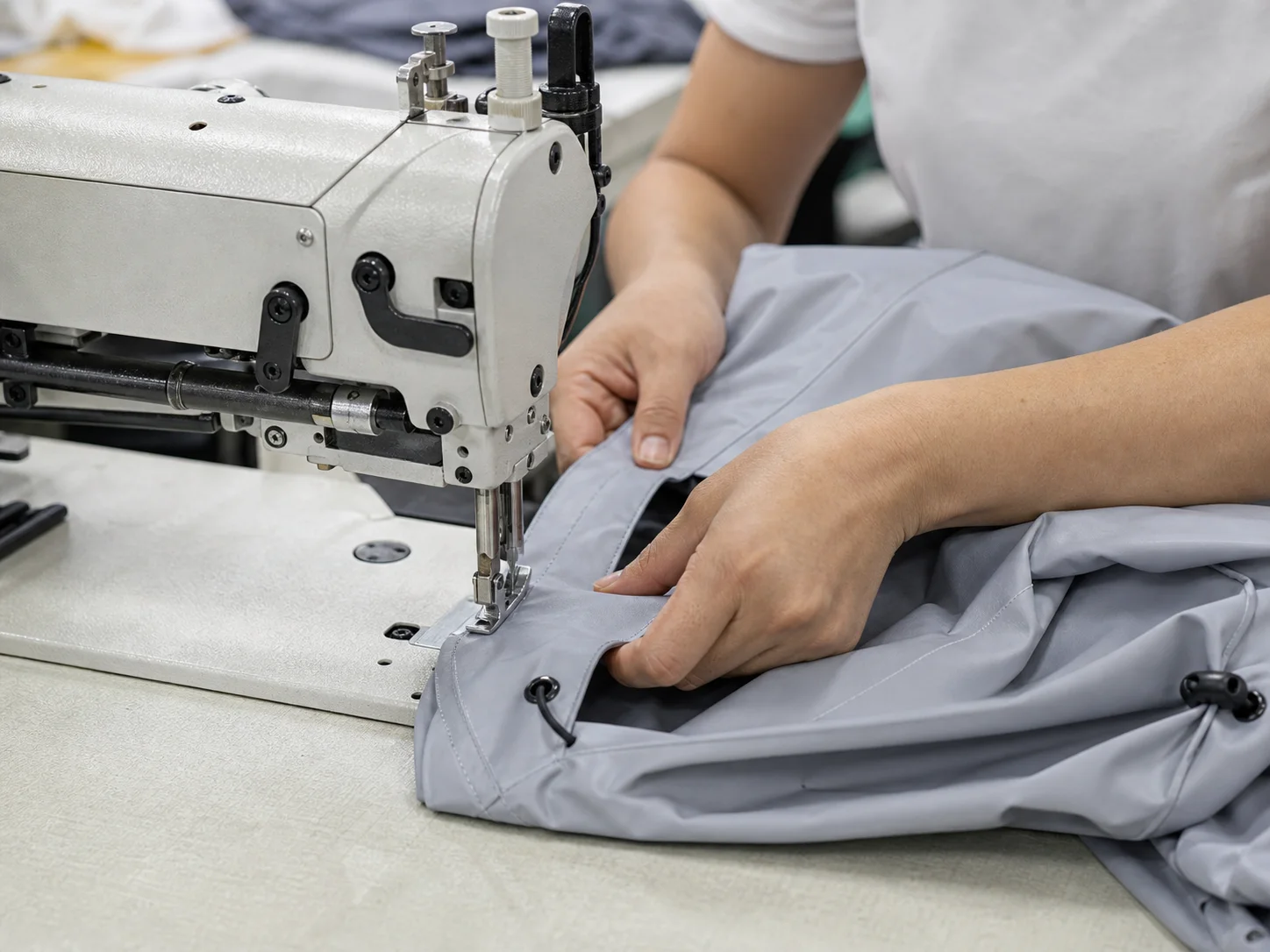 Technician sewing the drawstring channel of an outdoor jacket
